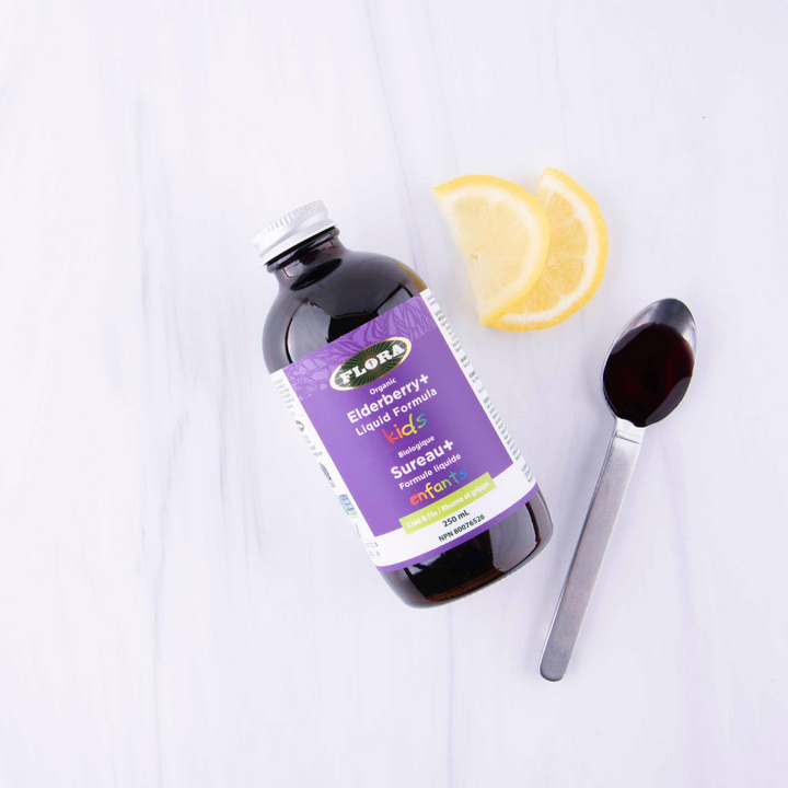 liquid elderberry supplement for kids and babies pictured with teaspoon and lemon slices