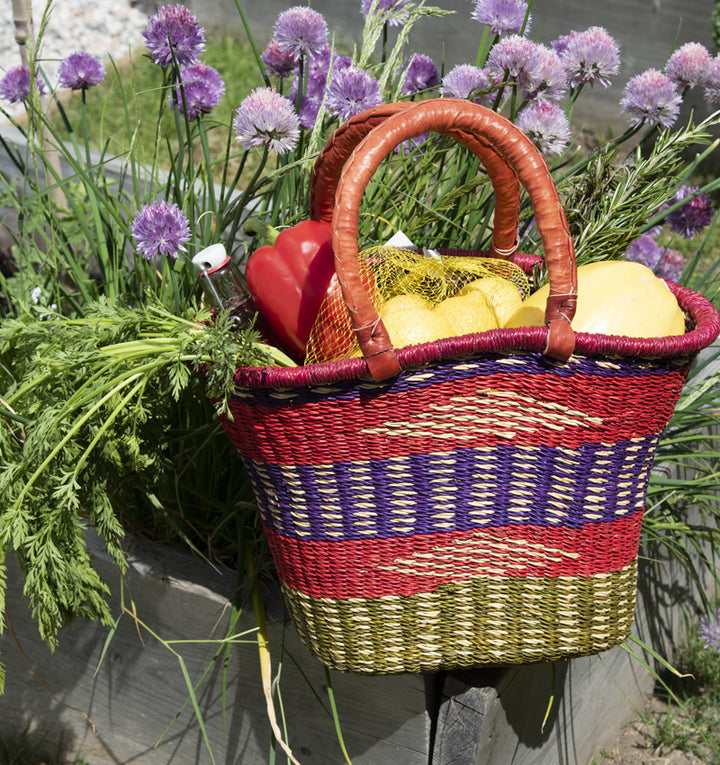 traditional west african hand basket in red, blue, and green full of produce